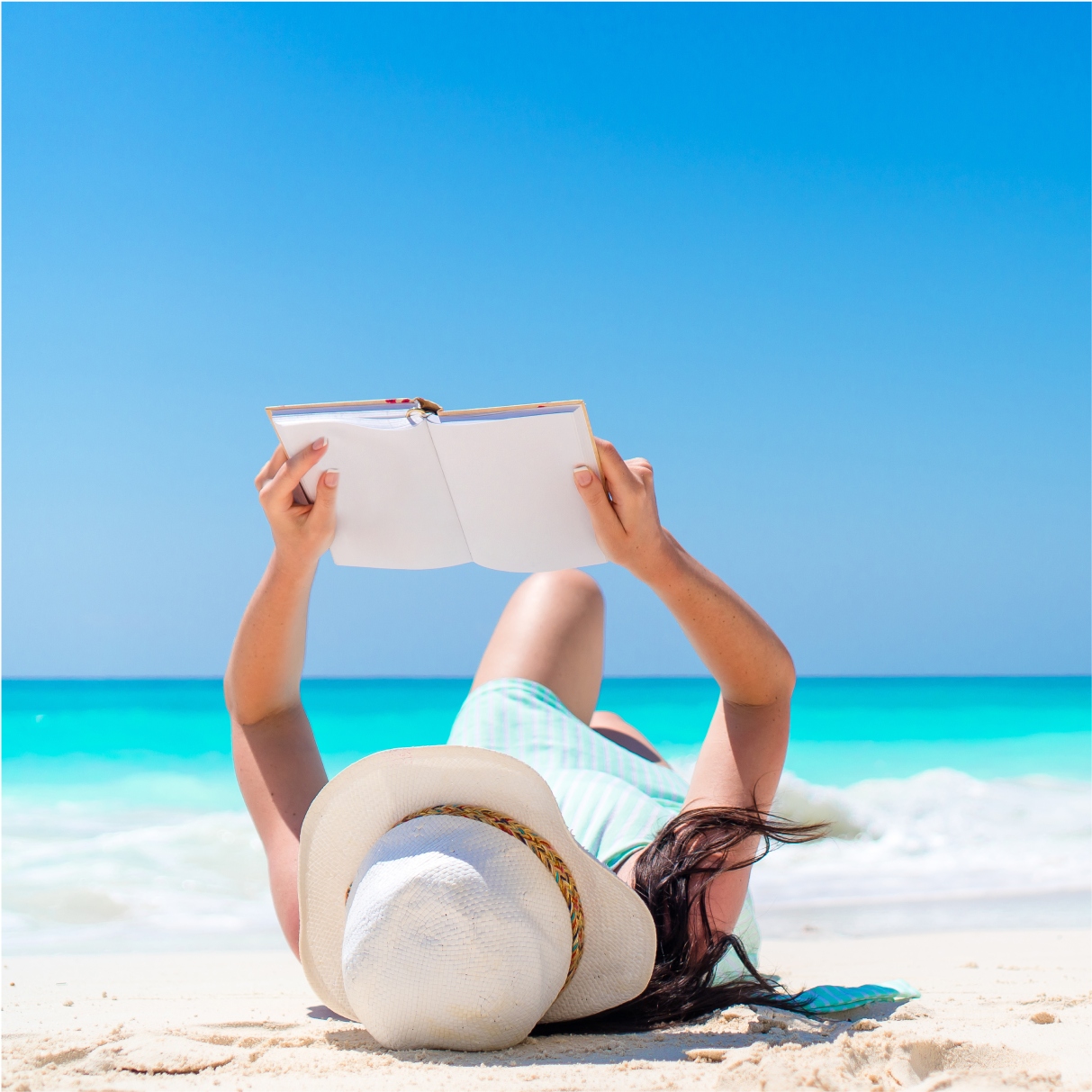 girl lying on the sand with a notebook